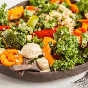 Veganer Bowl mit Quinoa, geröstetem Gemüse, Grünkohl, Tofu und cremigem Tahini-Dressing in einer dunklen Schale