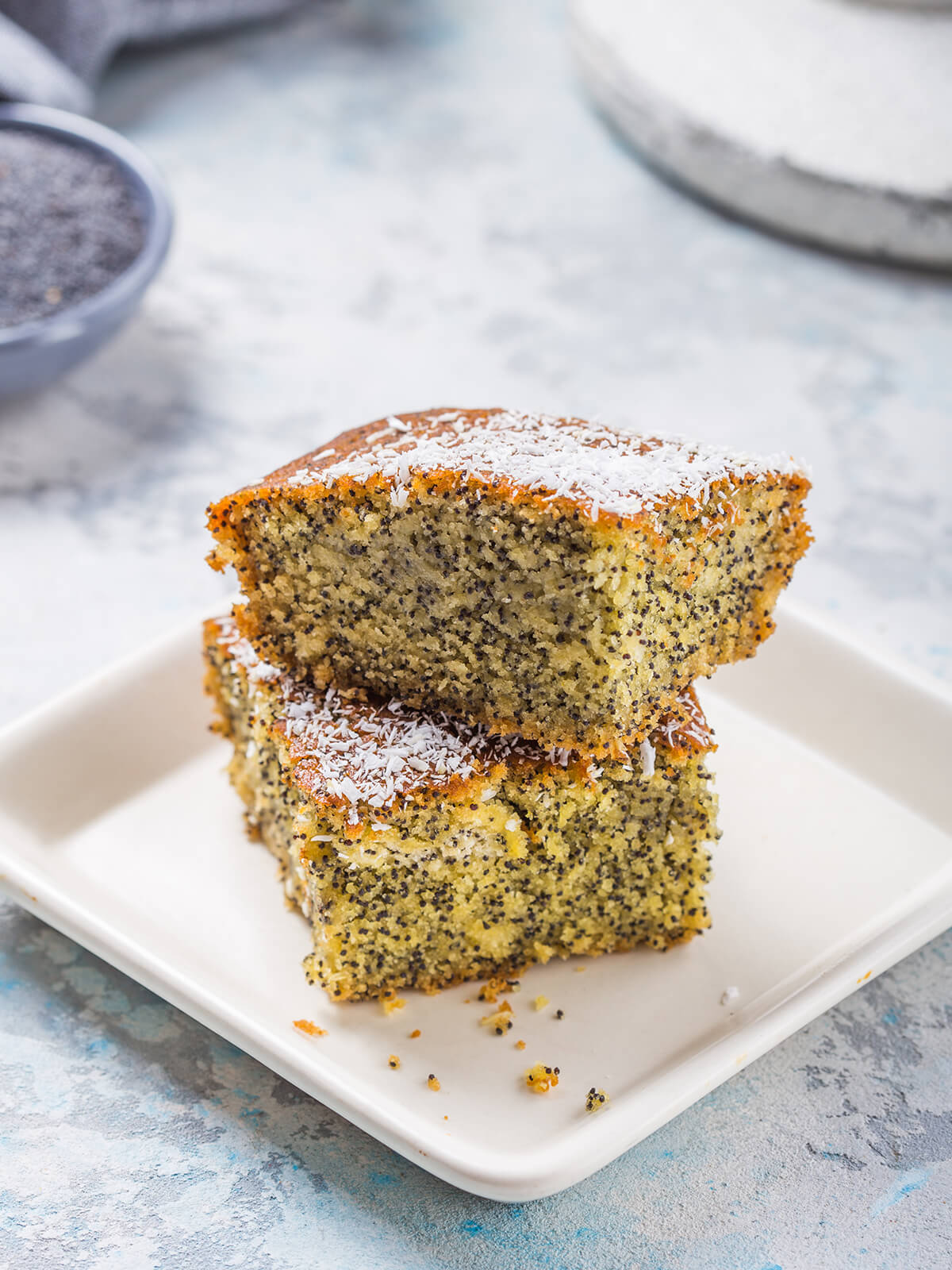 Gestapelte Stücke türkischer Grießkuchen mit Mohn (Revani), oben mit Kokosraspeln bestreut
