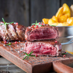 Steak medium rare aufgeschnitten mit rosa Kern, dazu knusprige Steakhouse-Pommes und Rosmarin