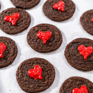 Mehrere weiche Schokoladen-Cookies mit glänzenden roten Schoko-Herzen von oben