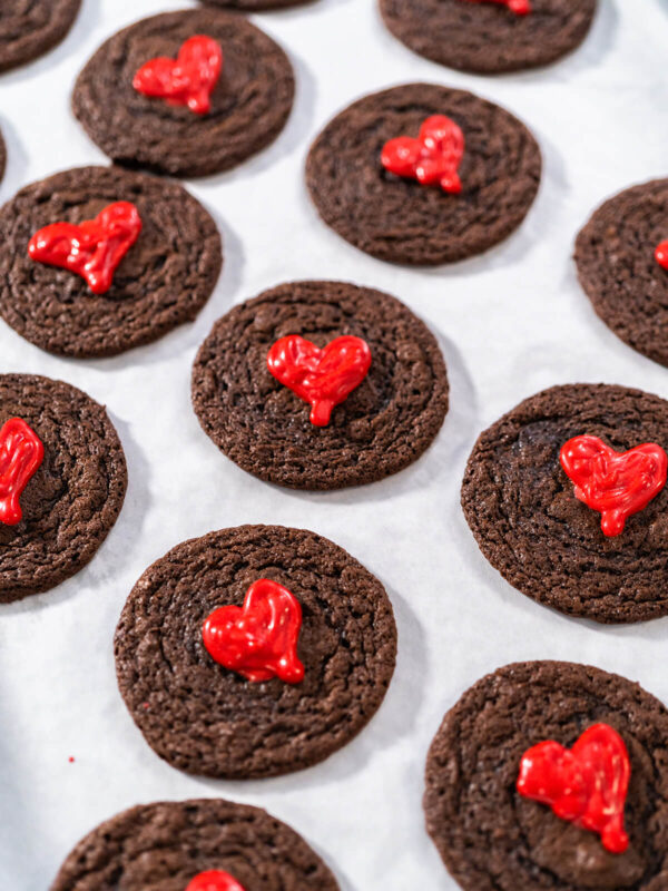 Mehrere weiche Schokoladen-Cookies mit glänzenden roten Schoko-Herzen von oben