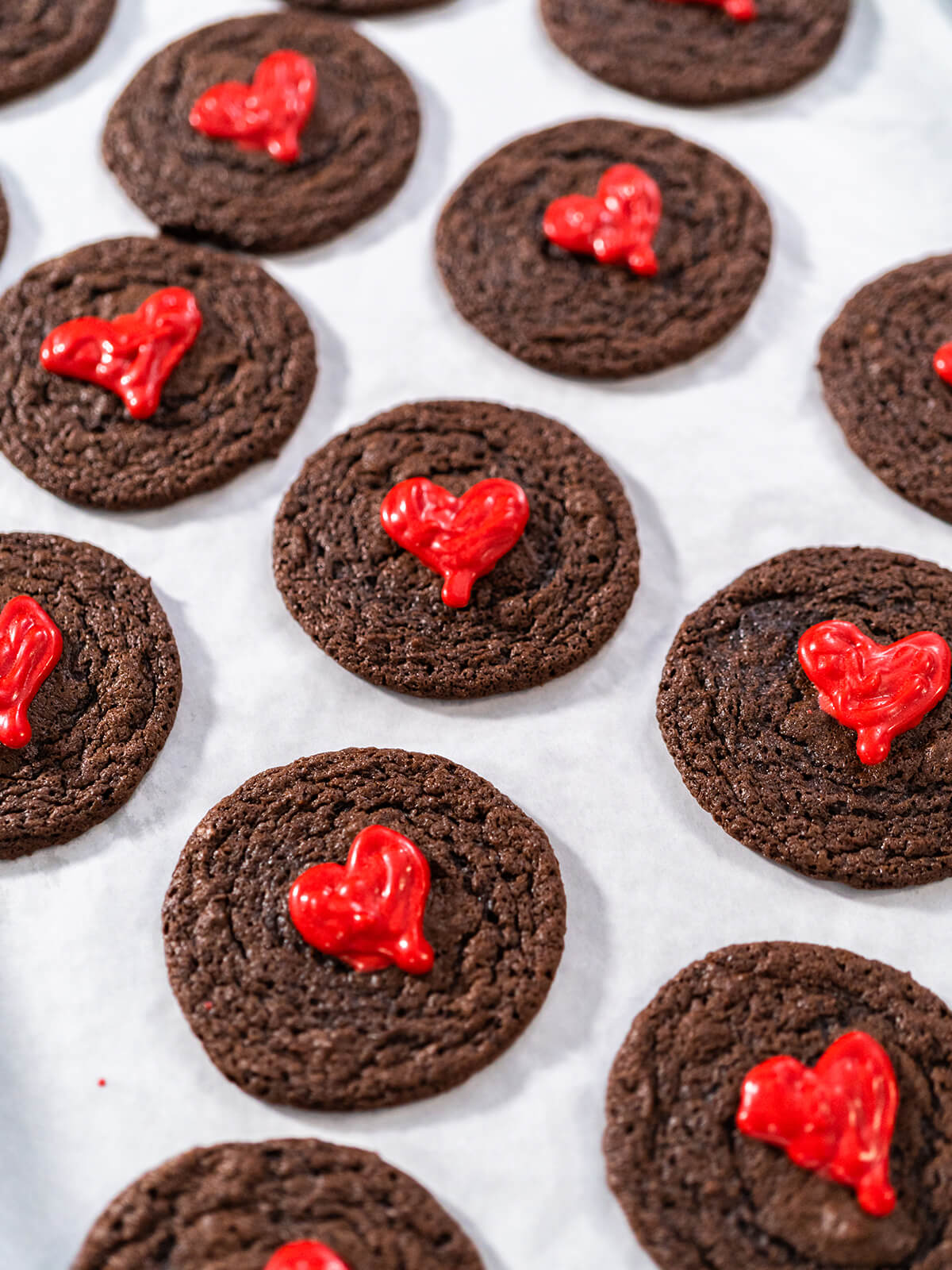 Mehrere weiche Schokoladen-Cookies mit glänzenden roten Schoko-Herzen von oben