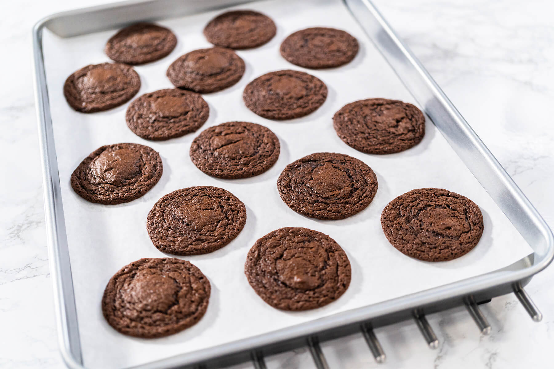 Fertig gebackene runde Schokoladen-Cookies auf einem Backblech mit Backpapier
