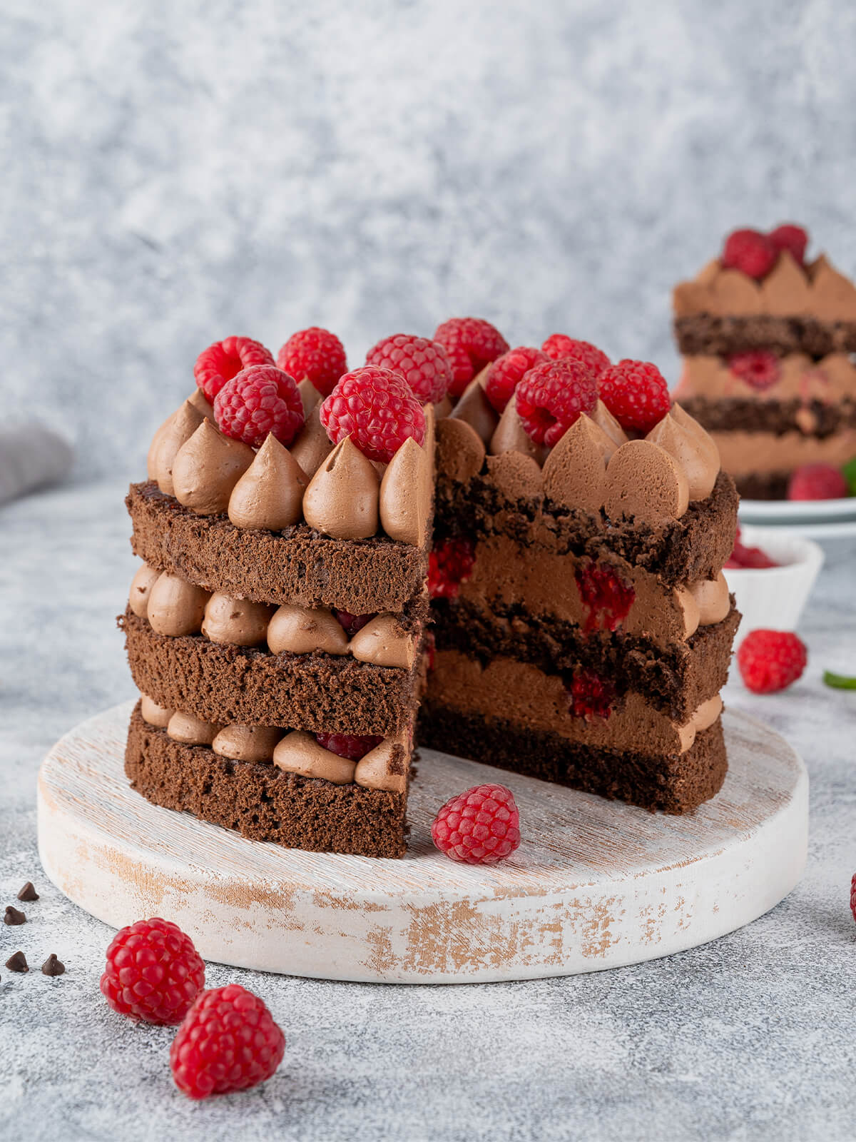 Angeschnittene Schoko-Himbeer-Torte mit drei Schokoladenbiskuits, Schokocreme und frischen Himbeeren zwischen den Schichten