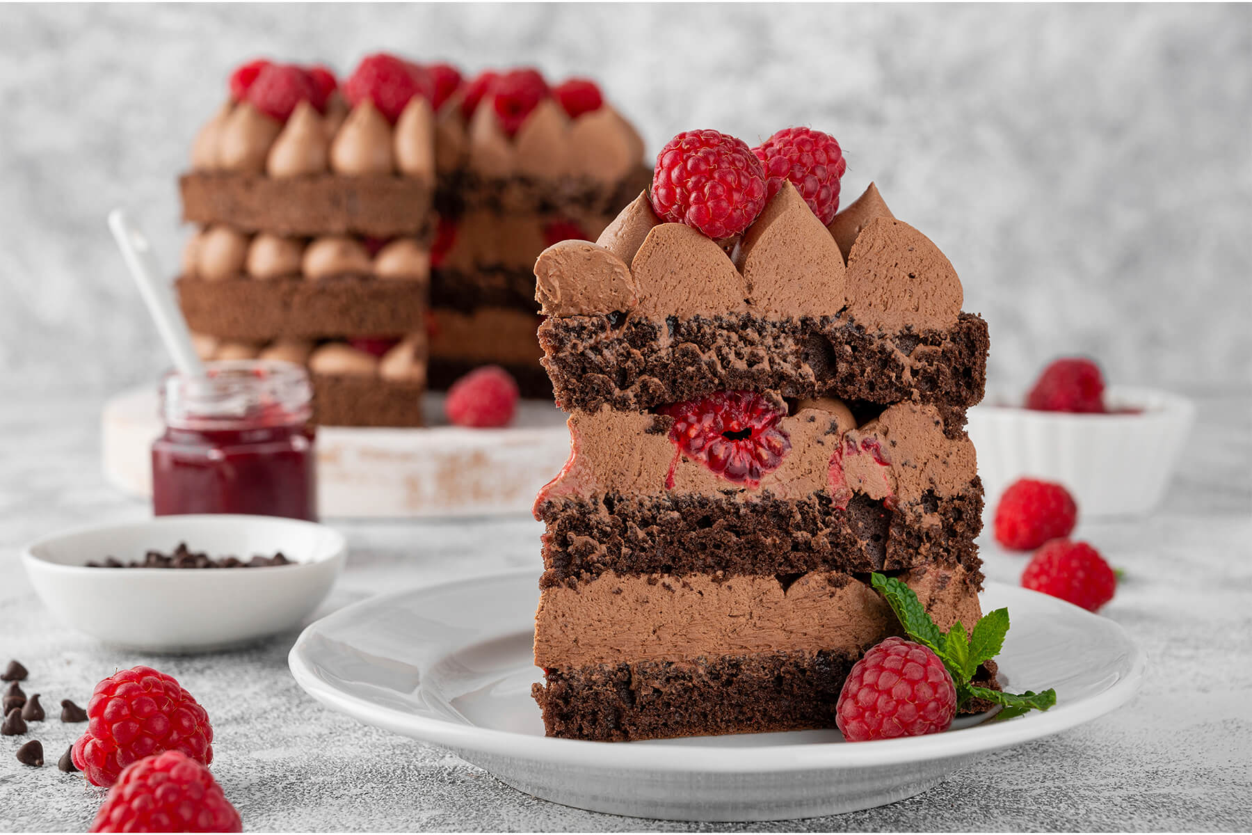 Tortenstück der Schoko-Himbeer-Torte von der Seite mit einer frischen Himbeere, die in der Schokocreme zwischen den Böden sitzt