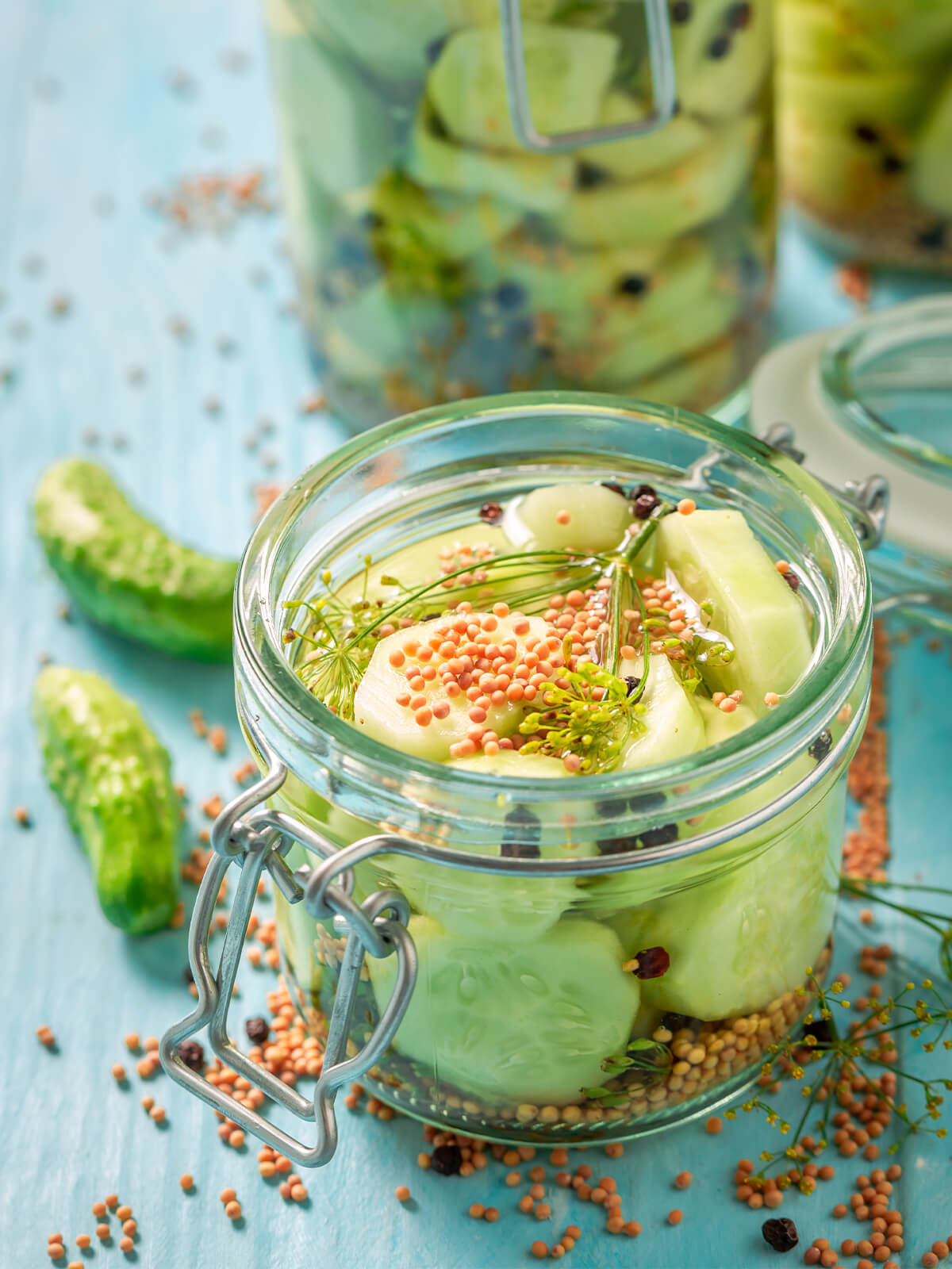 Offenes Glas mit süß-sauer eingelegten Gurkenstücken, gelben Senfkörnern, Piment und Dill
