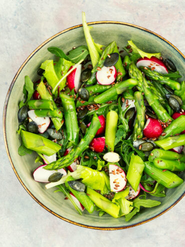 Grüner Spargelsalat mit Radieschen, Blattsalat, Kürbiskernen und Leinsamen in einer Schüssel von oben