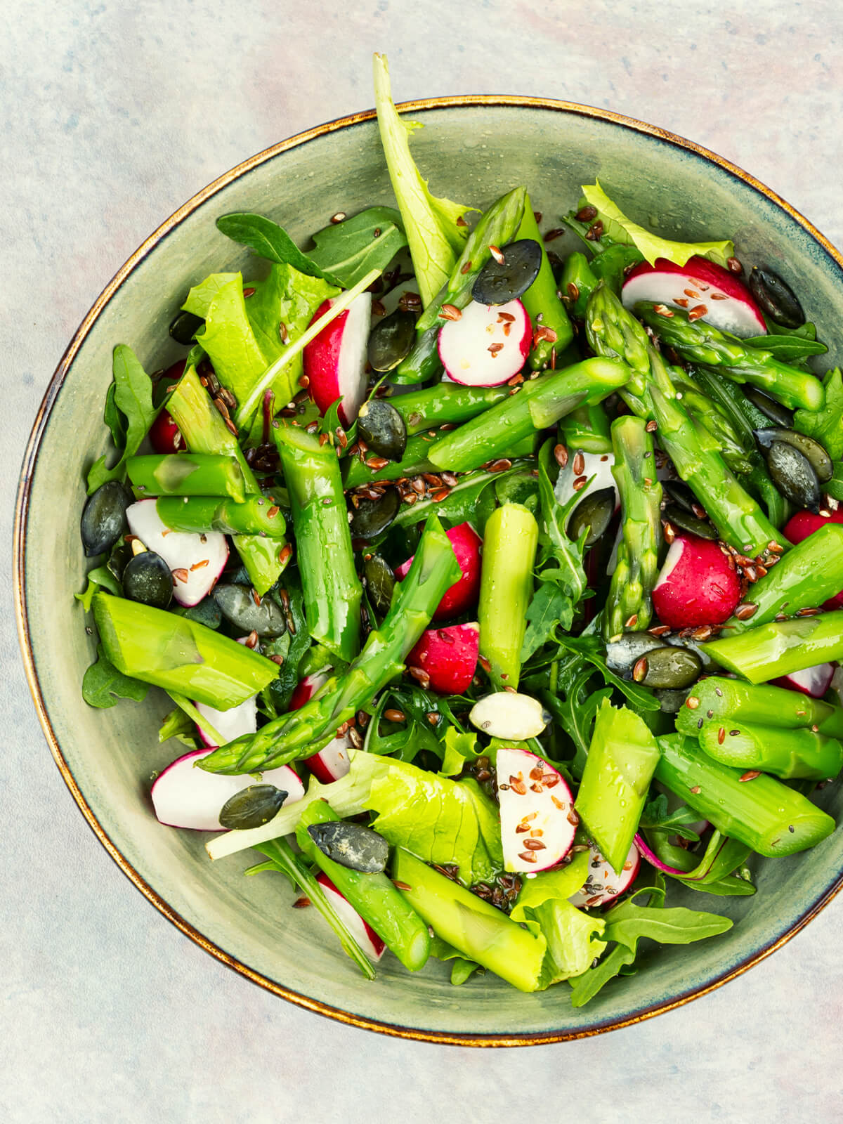 Grüner Spargelsalat mit Radieschen, Blattsalat, Kürbiskernen und Leinsamen in einer Schüssel von oben