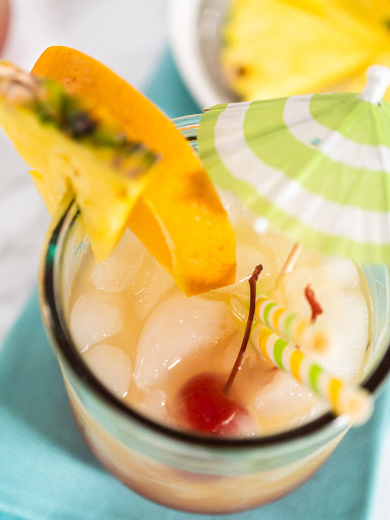 Tropischer Sunset-Cocktail mit Farbverlauf von Rot zu Gelb, Crush-Eis und Fruchtdeko von oben
