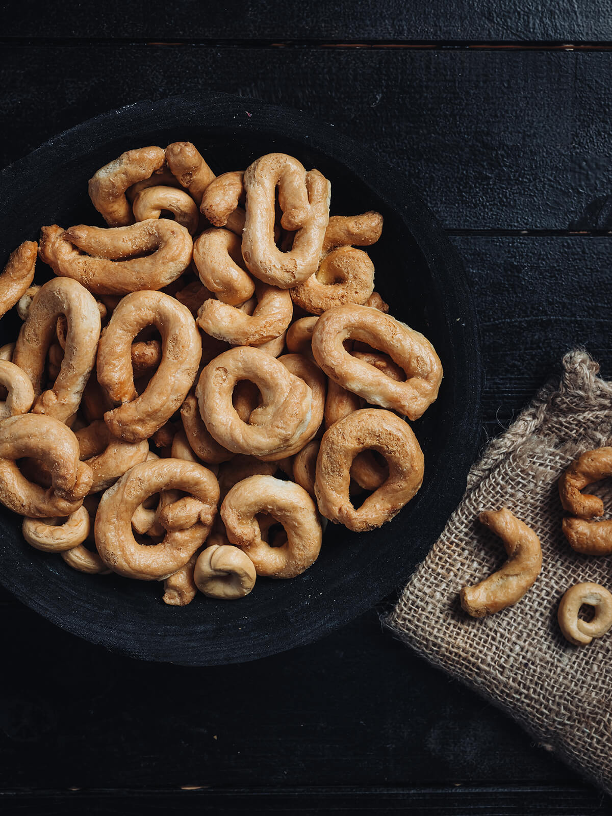 "Herzhafte Taralli Pugliesi von oben in einer dunklen Schale, goldbraune knusprige Teigkringel"