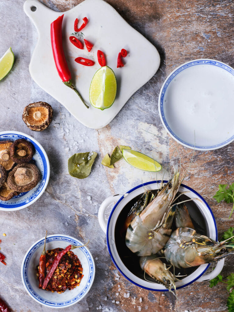 Zutaten für Tom Yam: ganze rohe Garnelen, Shiitake, rote Chili, Limette, Kaffirlimettenblätter und Kokosmilch