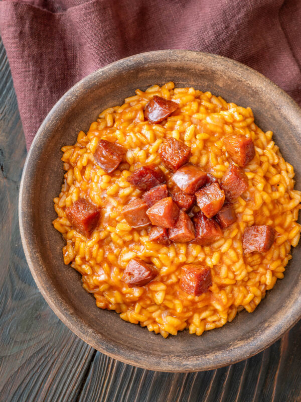 Cremiges Tomaten-Chorizo-Risotto mit knusprig gebratenen Chorizo-Würfeln in einer dunklen Keramikschale