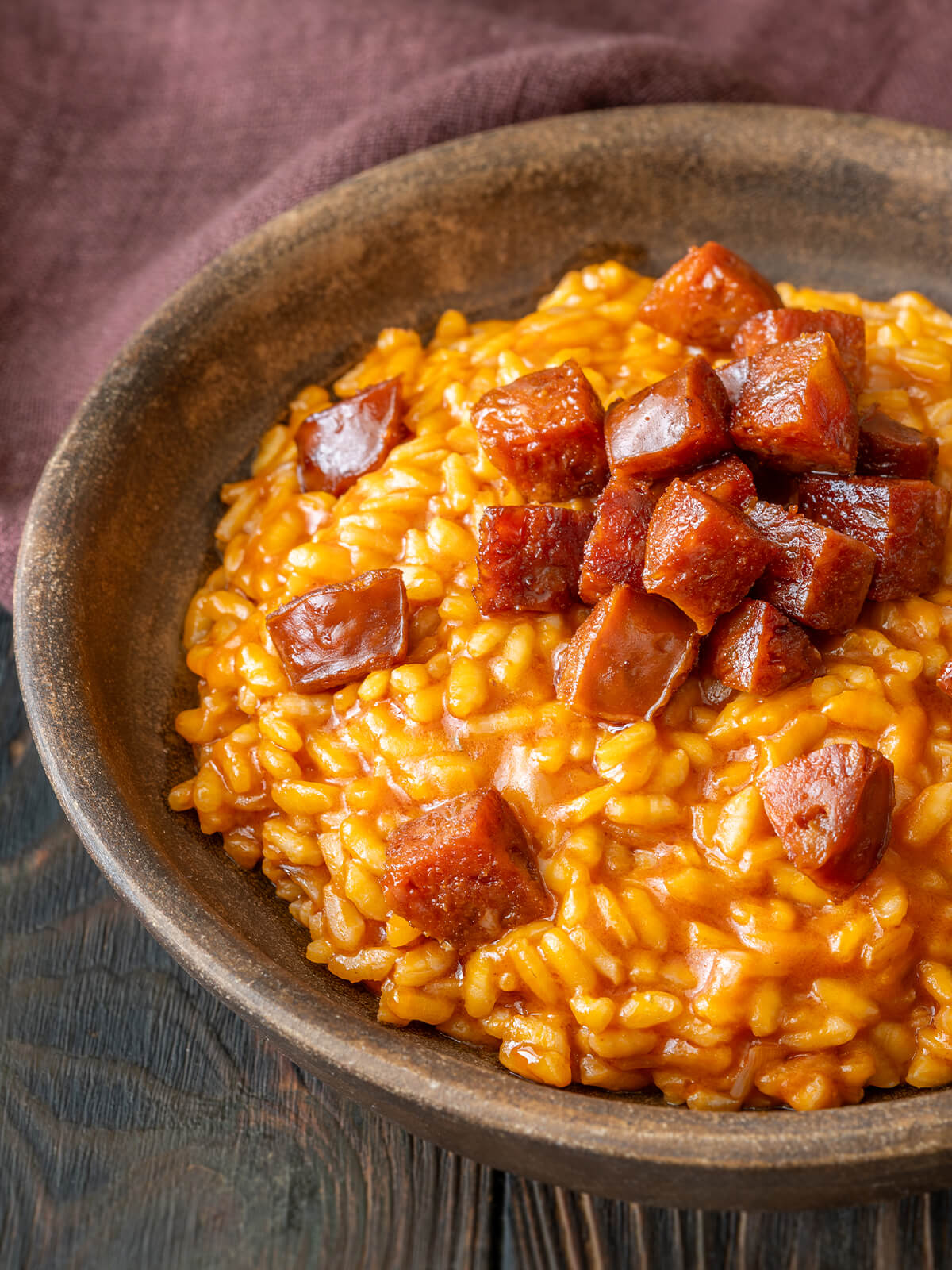 Schräge Nahaufnahme des cremigen Tomaten-Chorizo-Risottos mit glänzenden gebratenen Chorizo-Würfeln