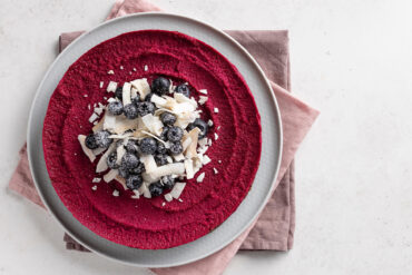 Vegane Rote-Bete-Torte mit kräftig beerenroter Füllung, dekoriert mit Blaubeeren und Kokoschips