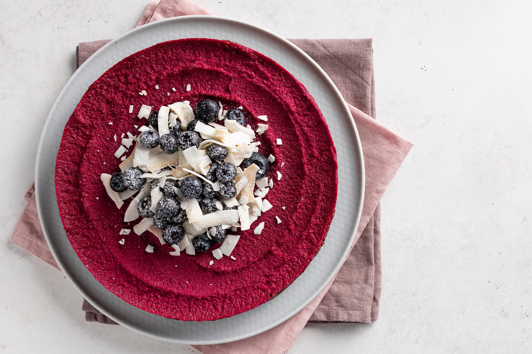 Vegane Rote-Bete-Torte mit kräftig beerenroter Füllung, dekoriert mit Blaubeeren und Kokoschips