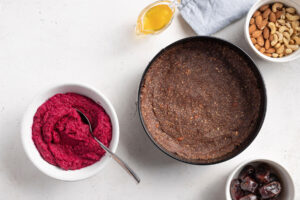Dunkler Nuss-Dattel-Boden für die vegane Rote-Bete-Torte, fest in eine Springform gedrückt