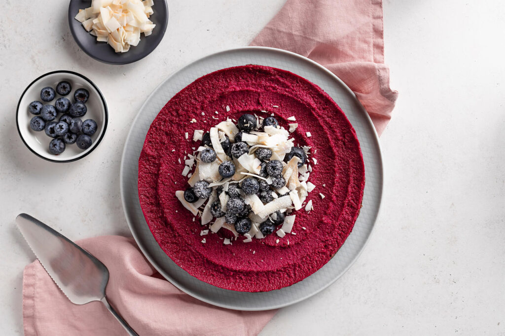 Fertige vegane Rote-Bete-Torte im Ganzen, in der Mitte mit Blaubeeren und Kokoschips garniert