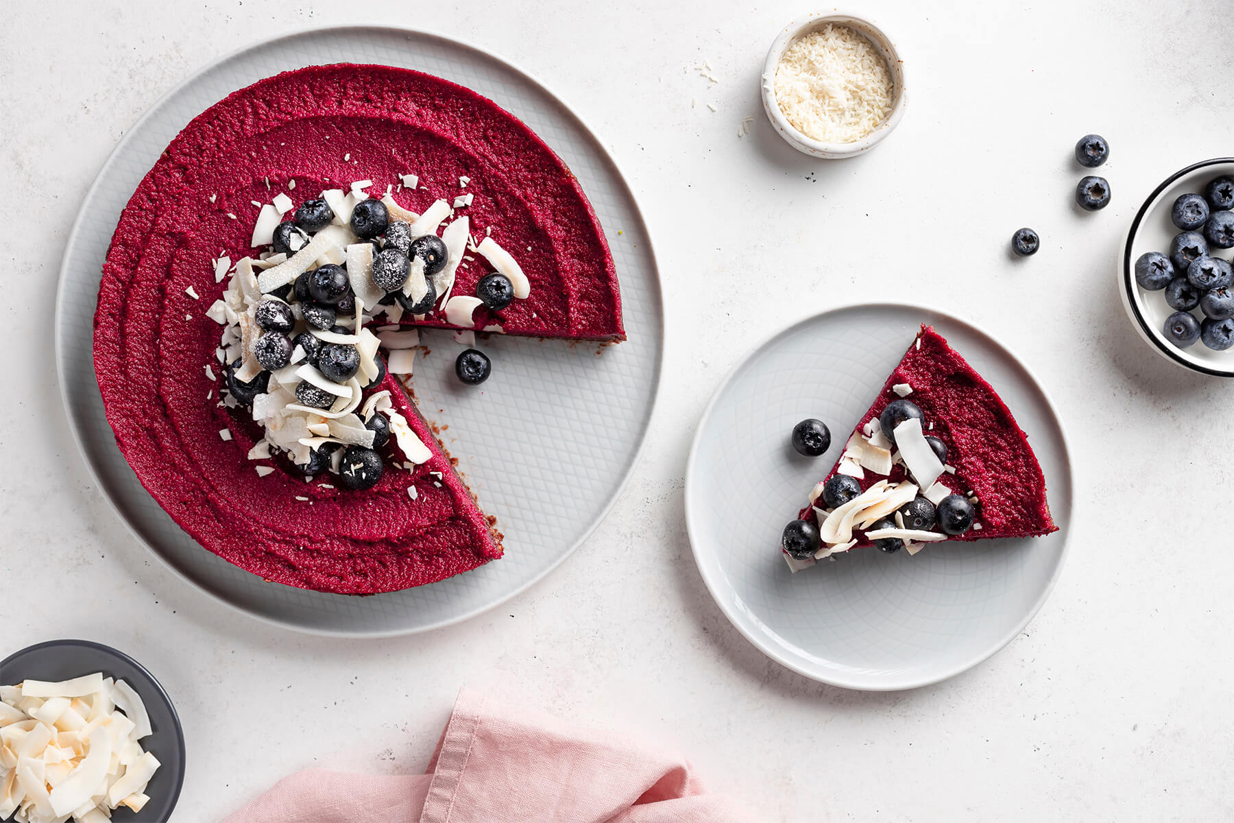 Vegane Rote-Bete-Torte mit Blaubeeren und Kokoschips, ein Stück auf einem separaten Teller angerichtet