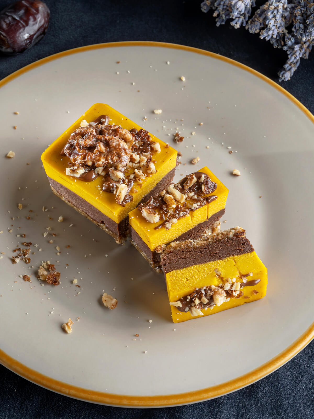 Vegane Kürbis-Schoko-Riegel mit Dattel-Nuss-Boden, Schokoladencreme und leuchtender Kürbisschicht, garniert mit Walnüssen