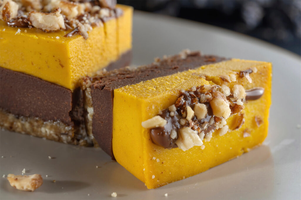 Vegane Kürbis-Schoko-Riegel auf einem Teller mit Walnüssen bestreut und mit Schokolade beträufelt