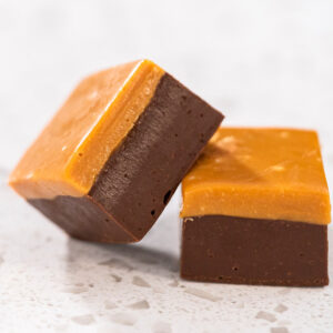 Zwei Würfel zweischichtiger Karamell-Fudge mit dunkler Schokoladen- und heller Karamellschicht in Nahaufnahme