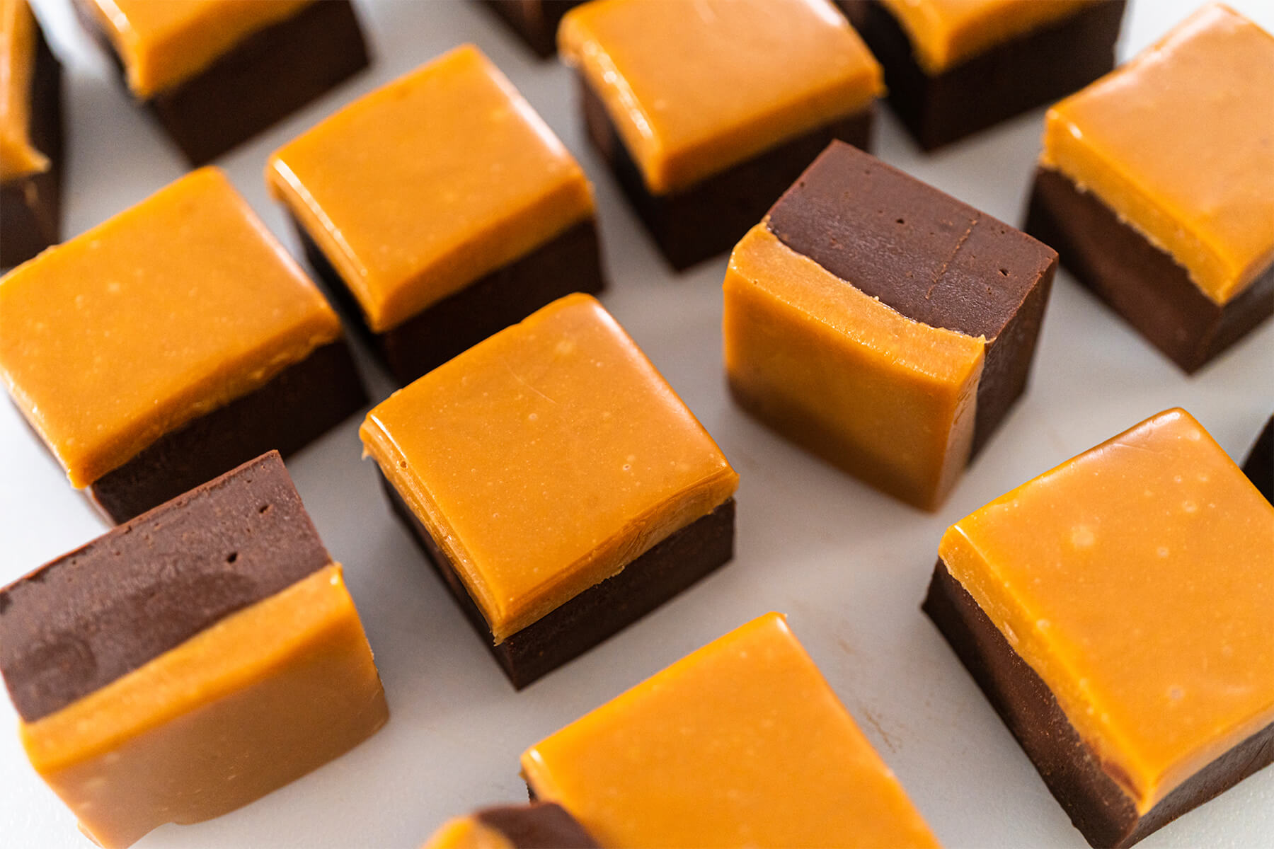 Viele fertige zweischichtige Karamell-Fudge-Würfel nebeneinander auf heller Fläche
