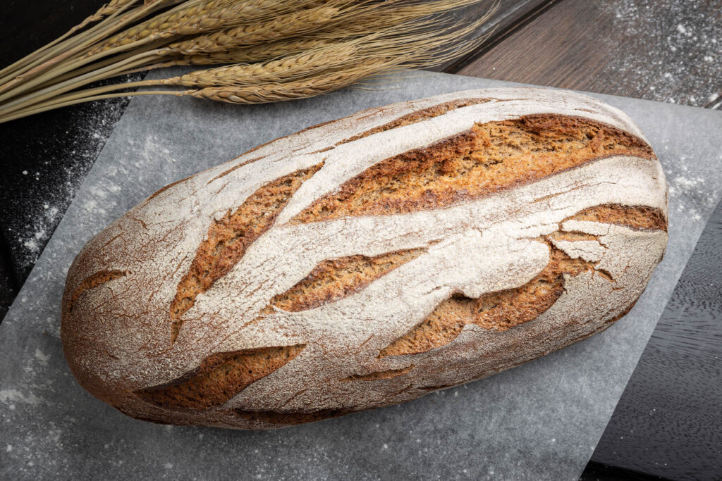Bemehlter ovaler Laib Bauernbrot mit Sauerteig mit schräg gesetzten Einschnitten von oben