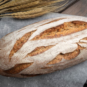 Bemehlter ovaler Laib Bauernbrot mit Sauerteig mit schräg gesetzten Einschnitten von oben