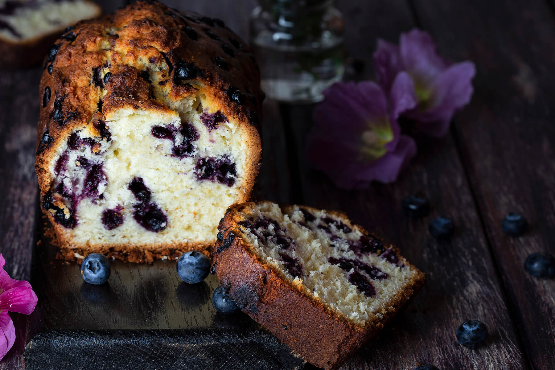 Angeschnittener Blaubeer-Limetten-Kastenkuchen mit ganzen Blaubeeren im hellen Butterteig