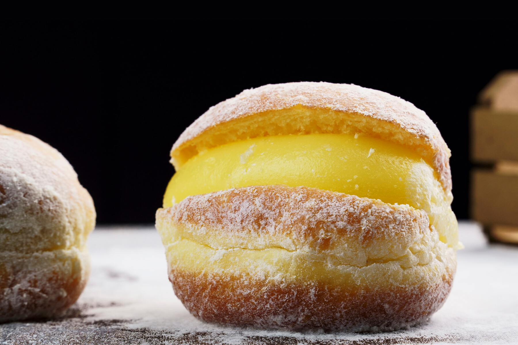 Brasilianischer Cremekrapfen im Anschnitt mit dicker gelber Vanillecreme zwischen zwei Teighälften