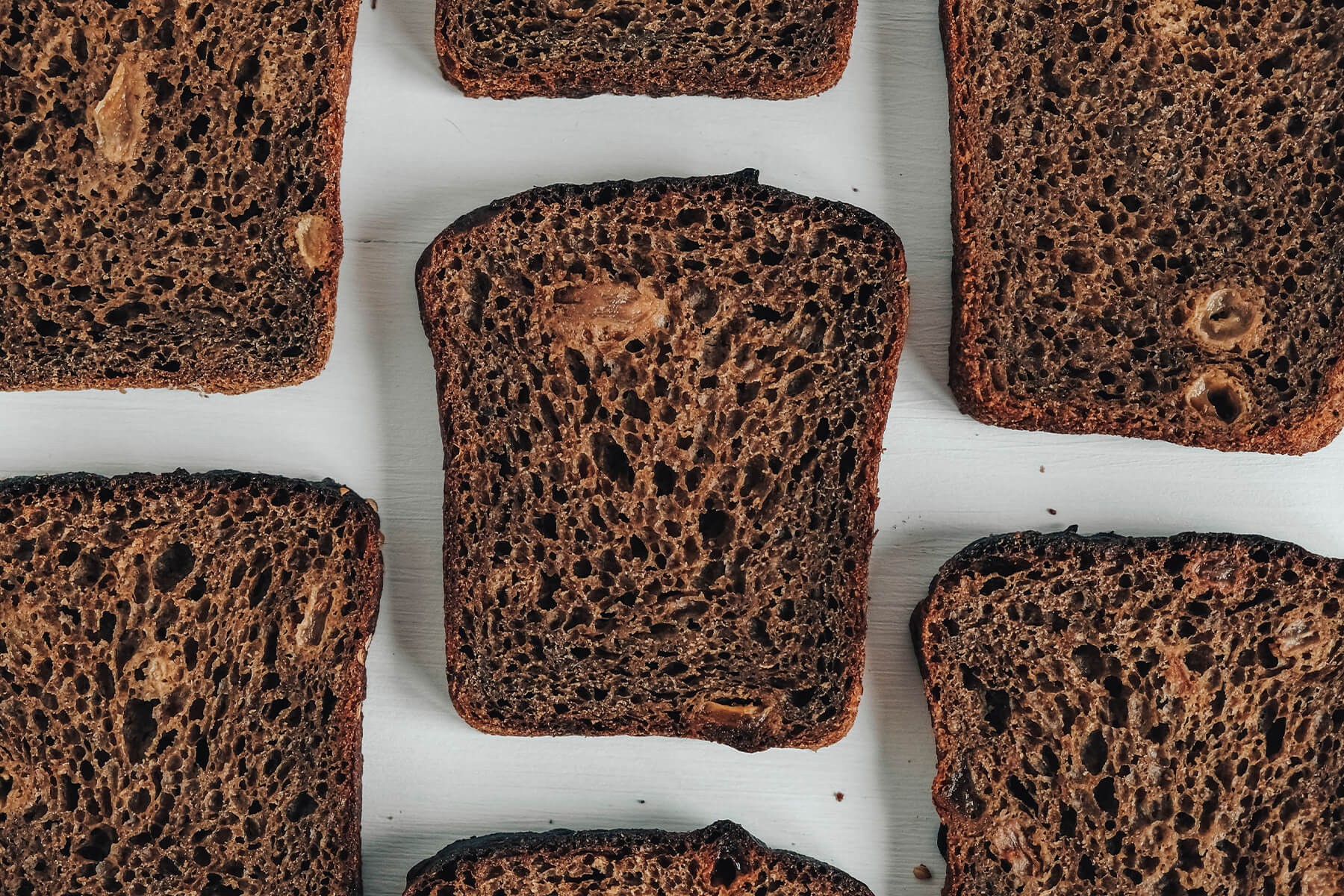 Scheiben von dunklem Roggenbrot von oben mit sichtbaren hellen Rosinenstücken in der Krume