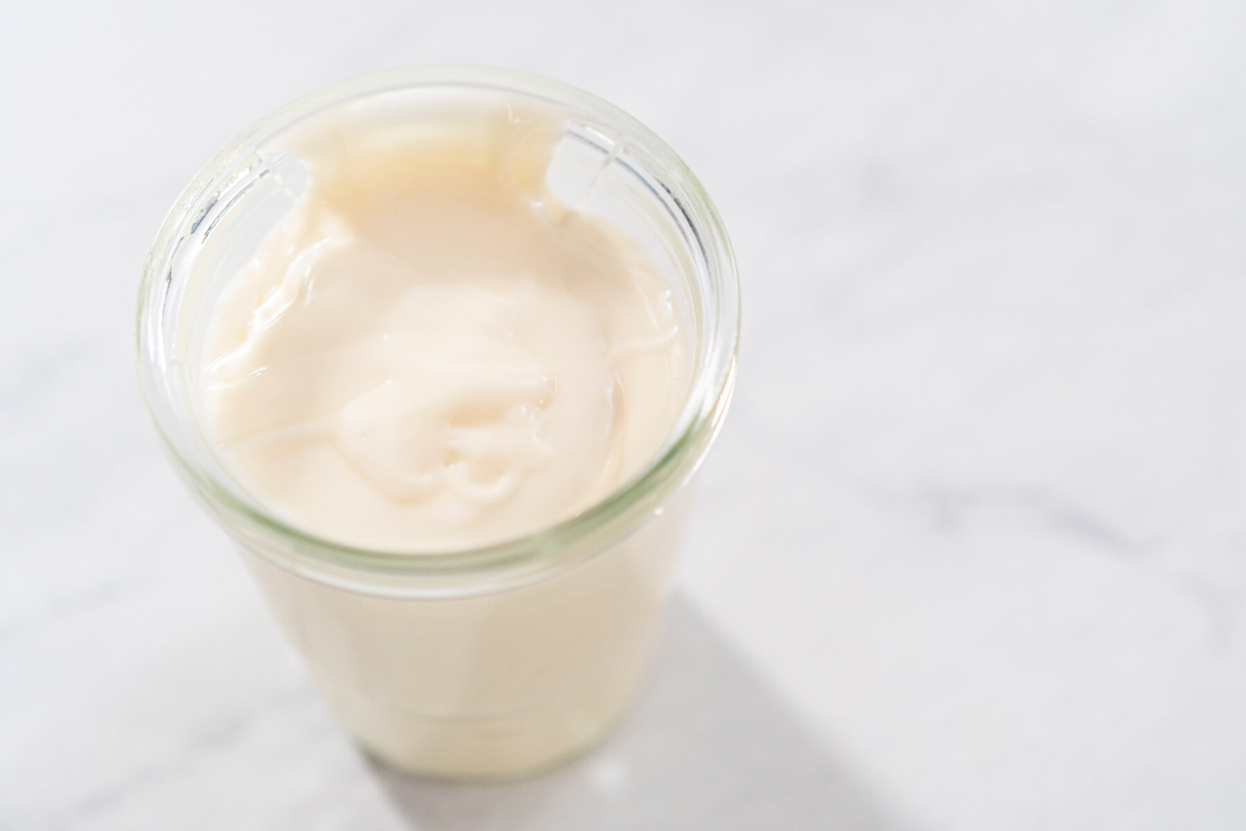 Blick von oben in ein Glas mit heller Frischkäse-Glasur