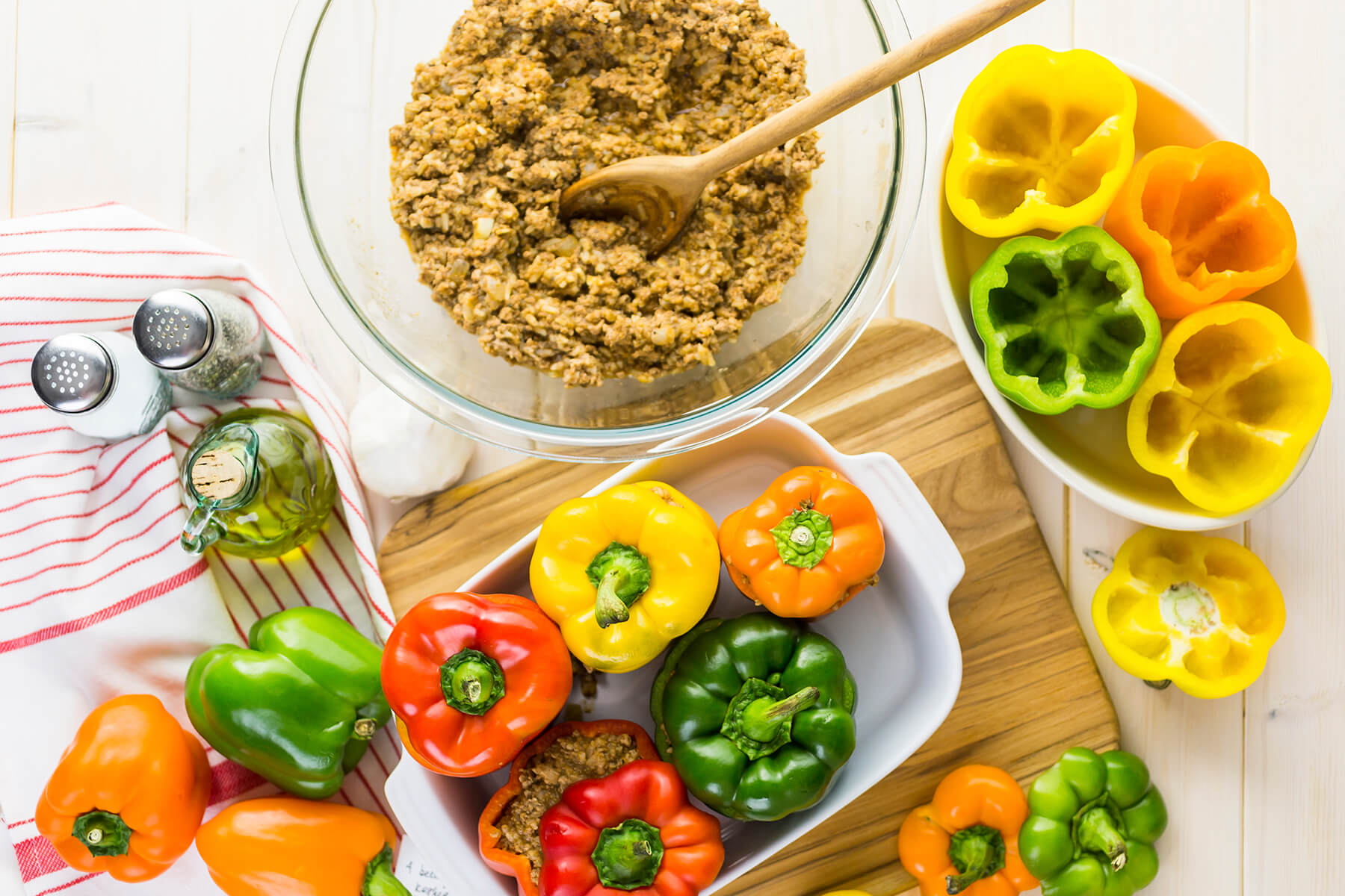 Fertig vermengte Füllung aus Putenhack und gekochtem Reis in einer Glasschüssel neben ausgehöhlten bunten Paprika