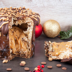 Angeschnittener Panettone mit dickem Karamellkern, Vollmilchglasur, hellen Zuckerstreifen und Karamellperlen auf der Kuppe