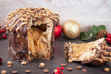 Angeschnittener Panettone mit dickem Karamellkern, Vollmilchglasur, hellen Zuckerstreifen und Karamellperlen auf der Kuppe