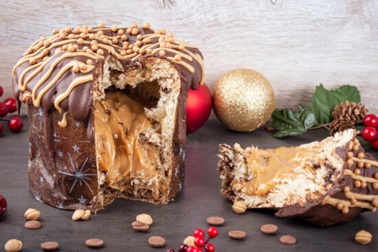 Angeschnittener Panettone mit dickem Karamellkern, Vollmilchglasur, hellen Zuckerstreifen und Karamellperlen auf der Kuppe