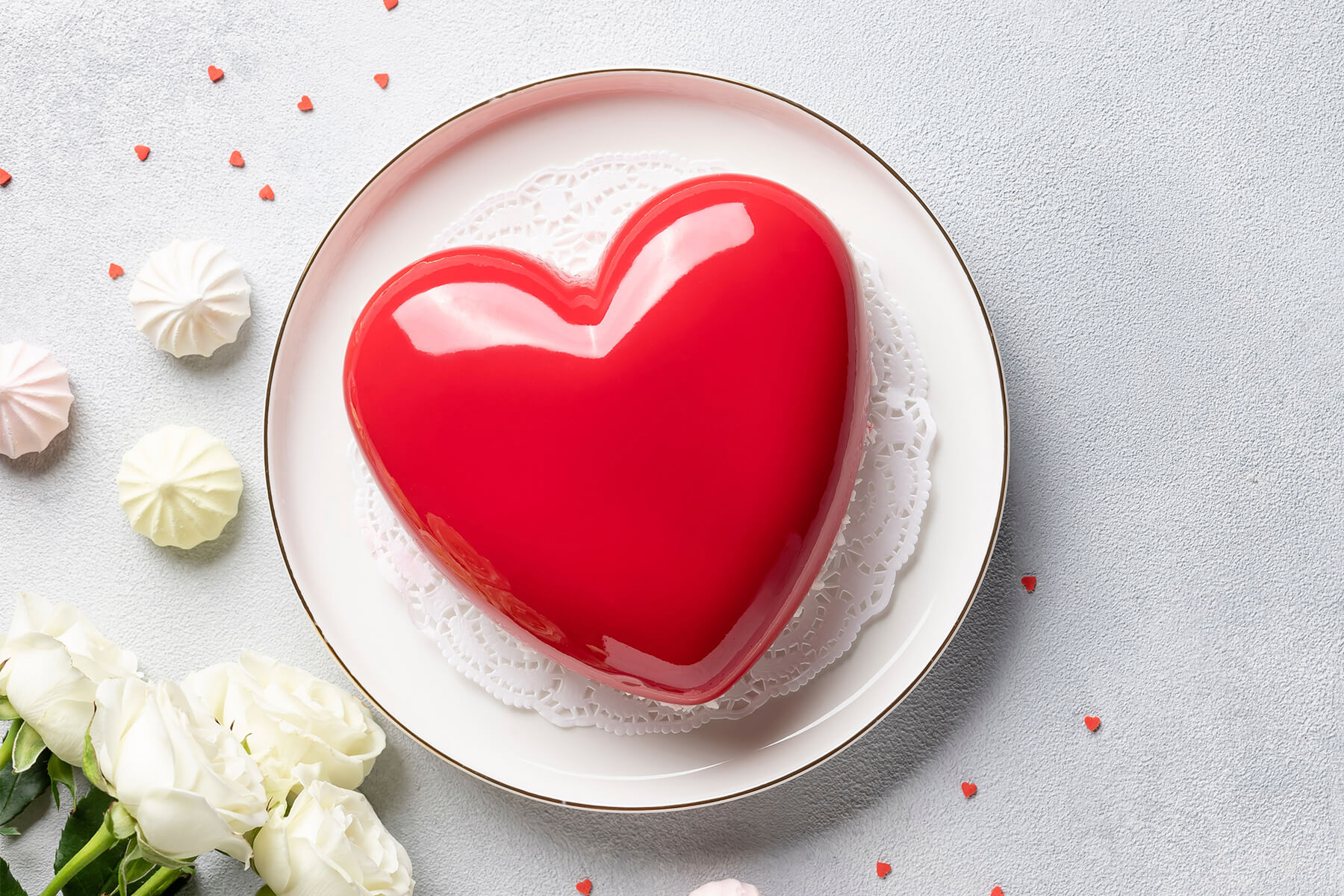 Herz-Mousse-Torte mit spiegelnder roter Glasur auf einem hellen Teller