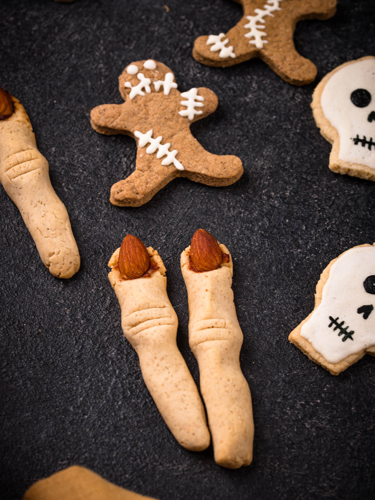 Hexenfinger-Kekse zusammen mit Lebkuchenmännern und Kürbis-Keksen auf einem Halloween-Partytisch