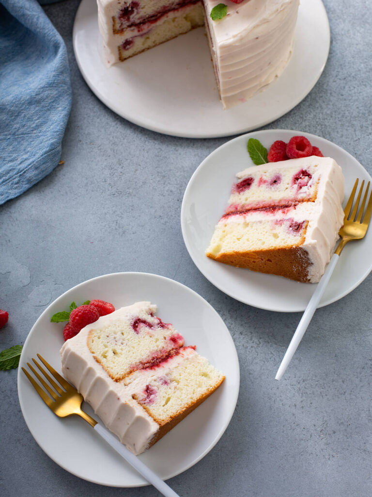Zwei Stücke Himbeertorte auf weißen Tellern mit sichtbarer Linie aus Himbeerkonfitüre