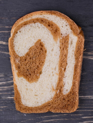 Scheibe japanisches Milchbrot mit Kakao-Marmorierung auf dunklem Holzbrett