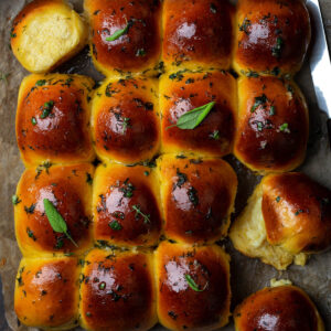 Sechzehn Knoblauchbrötchen mit Mozzarella-Füllung als zusammengewachsener Block auf Backpapier, von oben fotografiert