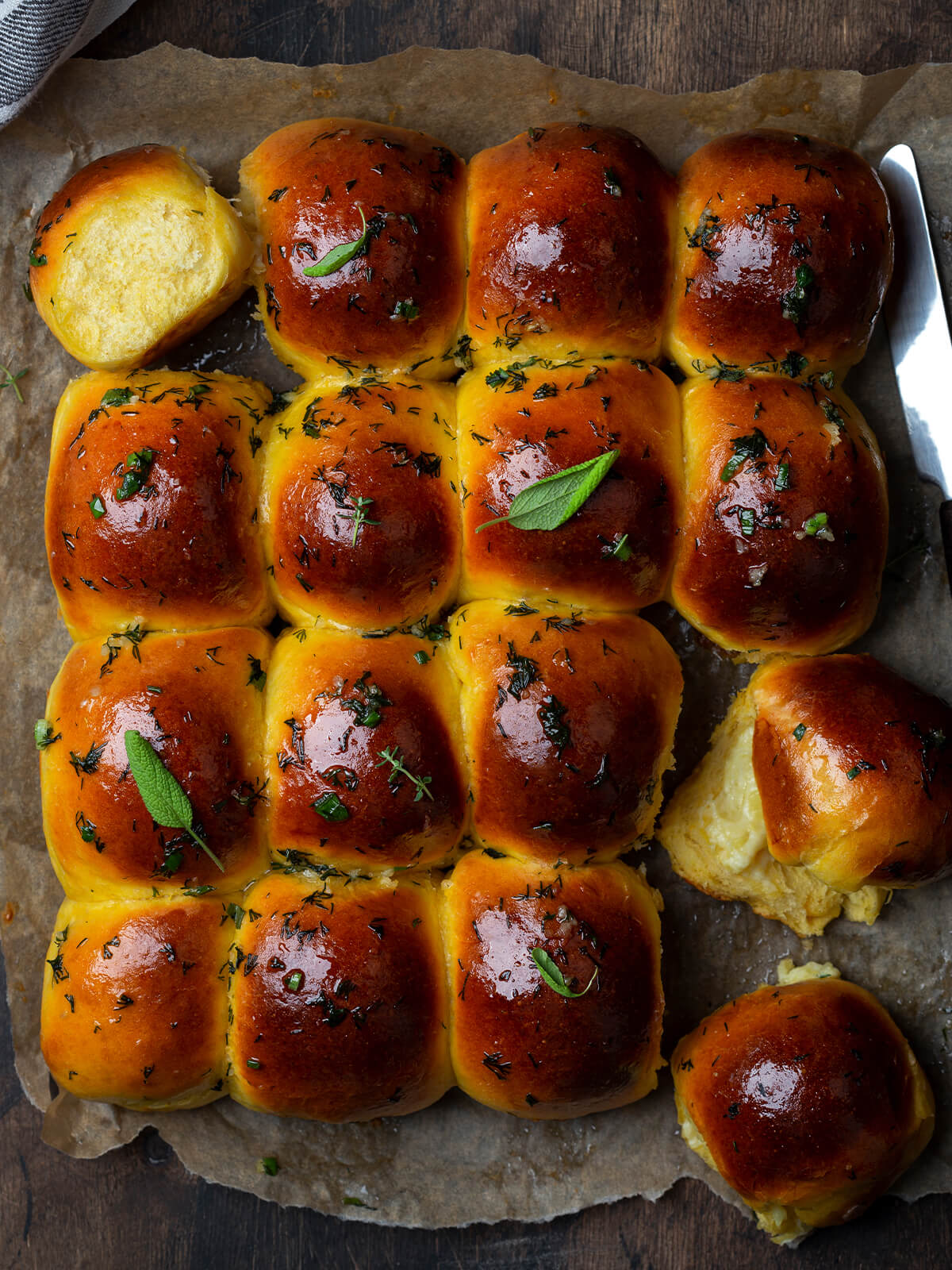Sechzehn Knoblauchbrötchen mit Mozzarella-Füllung als zusammengewachsener Block auf Backpapier, von oben fotografiert