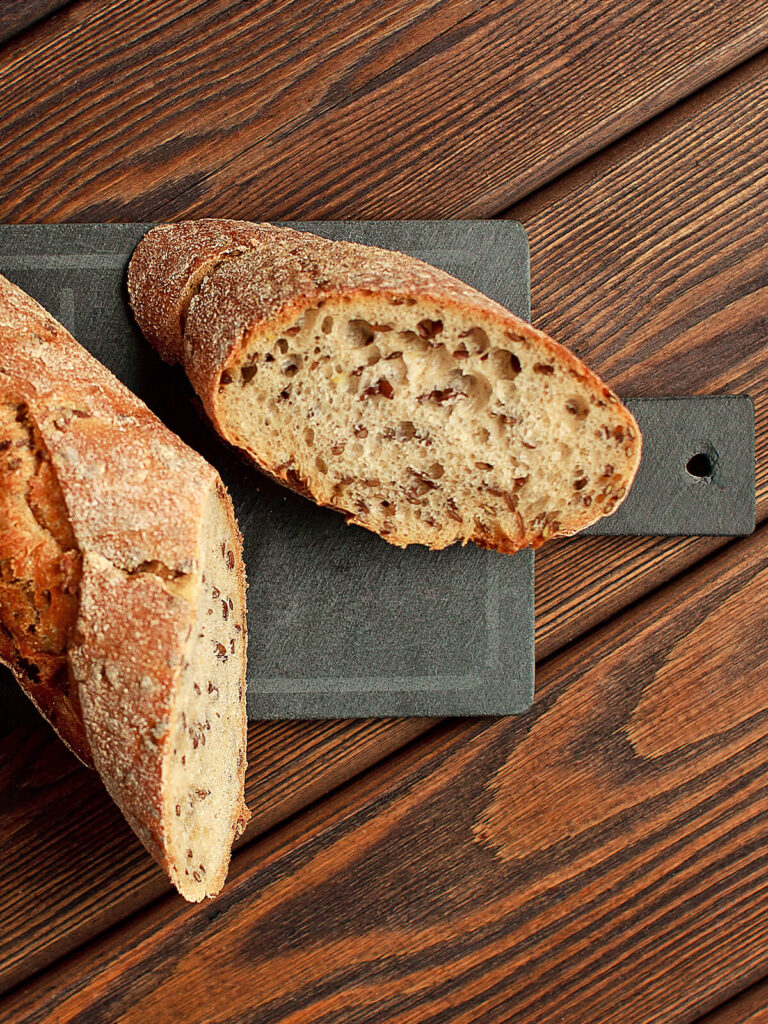 Nahaufnahme der feinporigen Krume eines Leinsamen-Baguettes mit sichtbaren braunen Samen