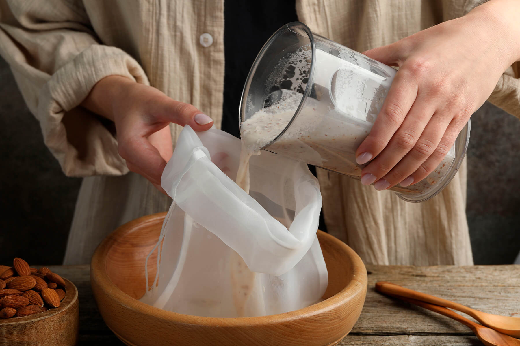 Gemixte Nussmasse wird aus dem Mixbehälter in einen Nussmilchbeutel gegossen