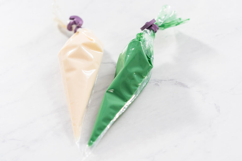 Zwei Spritzbeutel mit weißer und grüner Schmelzglasur