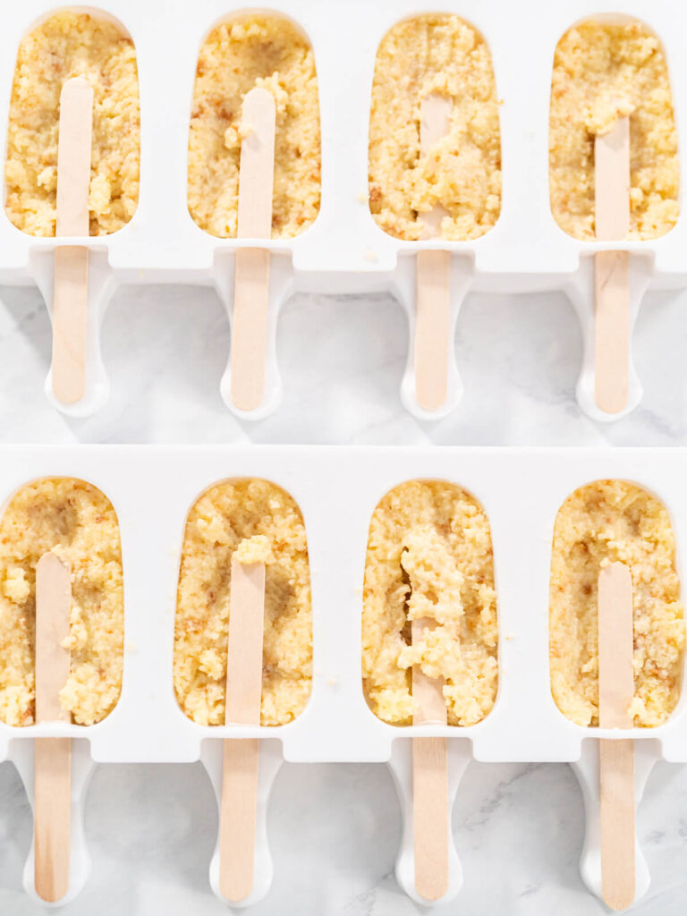 Zwei befüllte Cakesicle-Formen von oben mit eingesetzten Holzstielen