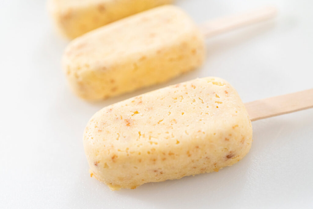 Entformte, ungetauchte Cakesicle-Rohlinge aus Kuchenmasse am Holzstiel