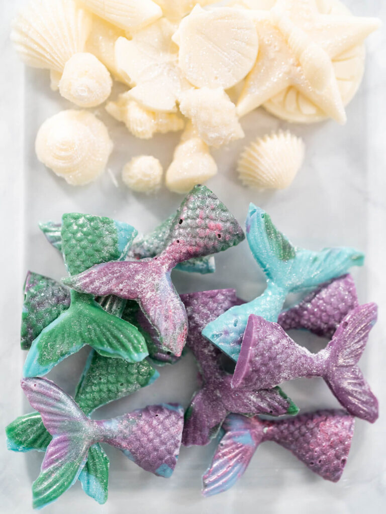 Weiße Schokomuscheln und marmorierte Meerjungfrauenflossen mit Perlglanz auf einer Platte