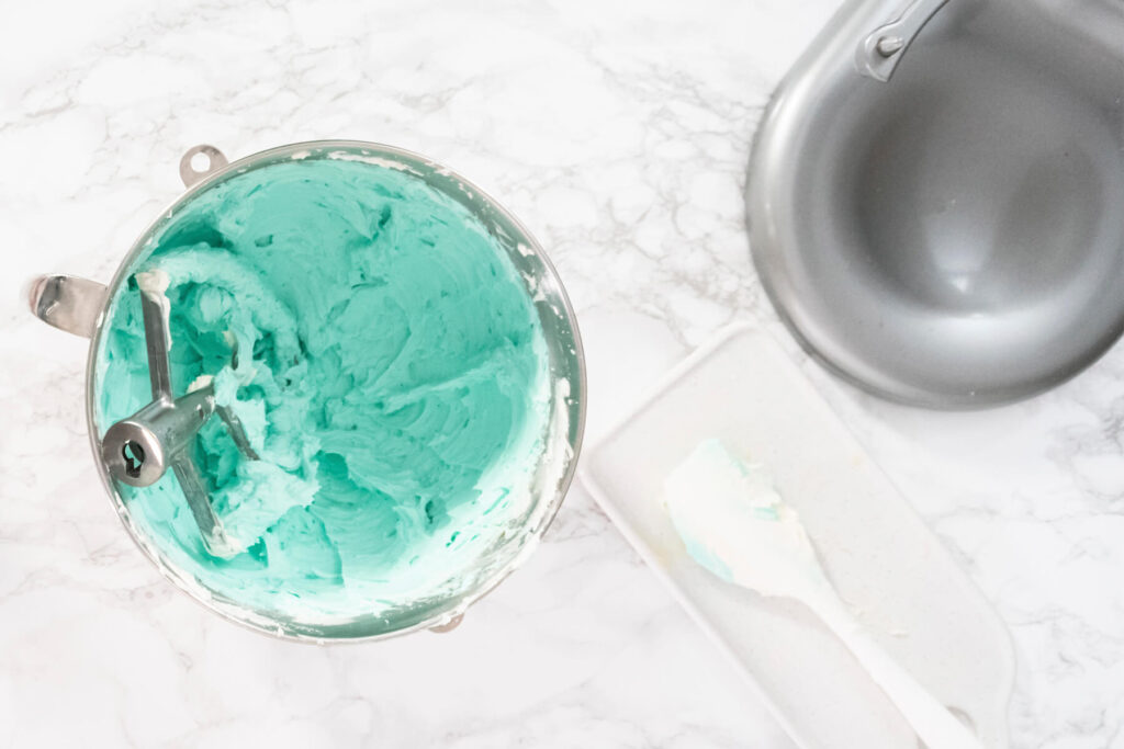 Türkis eingefärbte amerikanische Buttercreme in der Rührschüssel der Küchenmaschine