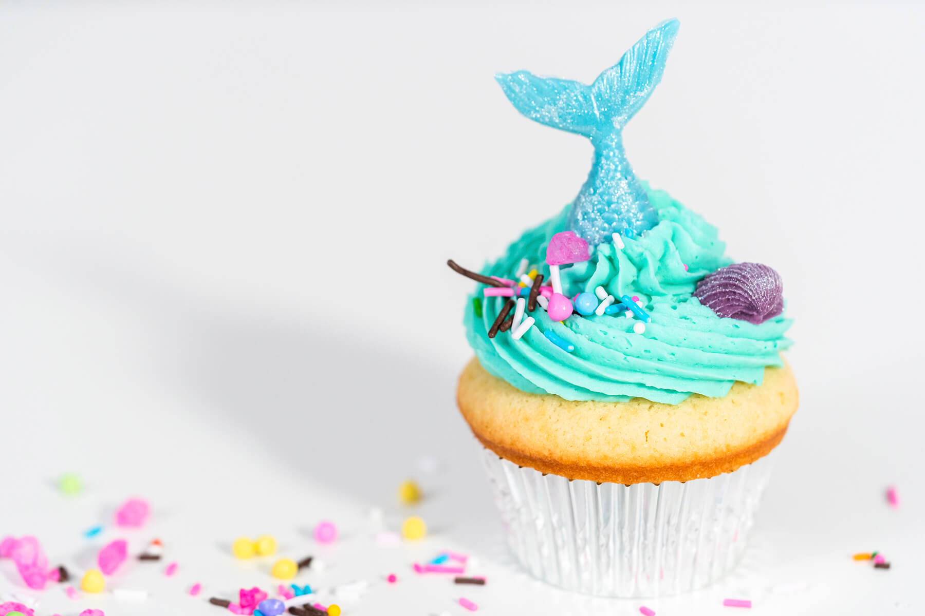 Nahaufnahme eines Meerjungfrauen-Cupcakes mit türkiser Buttercreme und schimmernder Flosse aus Schmelzglasur
